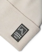 Gorro de punto tipo beanie en color gris claro, con diseño acanalado y parche rectangular con logo de la marca en la parte frontal.