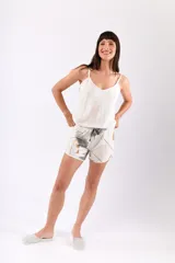 Pijama compuesto por una musculosa de breteles finos y un short con elástico en la cintura. La musculosa es de color liso, mientras que el short presenta un estampado de hojas en tonos gris y dorado sobre fondo color champagne.