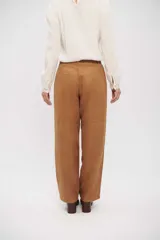 Pantalón de corte recto y tiro medio, confeccionado en tela con textura similar a la gamuza. Presenta bolsillos laterales, cierre frontal con botón y costura horizontal a la altura de la rodilla.