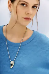 Remera azul de algodón peruano con textura jaspeada, de moldería holgada y buena caída, con mangas largas que se ajustan hacia la muñeca y se ensanchan debajo del brazo.