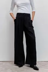 Pantalón de vestir negro con rayas verticales blancas, de corte recto y tiro alto.