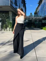 Pantalón negro de vestir con corte palazzo, cintura alta con lazo y abertura lateral.