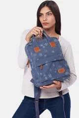 Mochila de lona azul con estampado floral, asas de mano superiores unidas por una tira con broche, detalles en cuero sintético marrón, bolsillo frontal con cierre y compartimentos laterales.