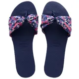 Sandalias tipo ojota Havaianas modelo You St Tropez, con base de goma azul marino y tira superior de tela con nudo decorativo y estampado floral en tonos rosas y blancos.
