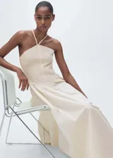 Vestido midi de diseño combinado con cuello halter y tirantes finos. Presenta un cuerpo superior de tejido texturizado con panel fruncido y una falda evasé de caída fluida. Incluye cierre de cremallera lateral.