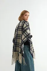 Ruana de tejido suave con diseño de cuadros grandes en tonos azul marino y beige, terminada con flecos en los extremos.