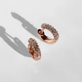 Par de aros tipo argolla ancha color oro rosa, con cristales incrustados en el frente.