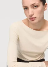 Camiseta de manga larga en color crema, con cuello redondo y ajuste al cuerpo.
