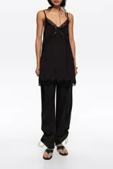 Pantalón jogger negro confeccionado en mezcla de lyocell y algodón, de tiro medio con bolsillos laterales y bajos ajustables mediante cordones elásticos con stoppers.