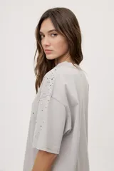 Remera oversized de manga corta y cuello redondo, de color negro con efecto acid wash y aplicación de strass en la parte superior.