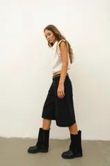 Bota de cuero negra con caña alta y detalle volcado en la parte superior. Taco bajo y puntera redondeada.