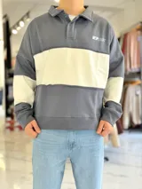 Buzo de cuello polo y medio cierre, con diseño de bloques de color en gris y blanco, de corte oversize y mangas largas.