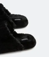 Pantufla cerrada de mujer con textura de peluche suave en color negro, diseñada para brindar comodidad en el hogar.