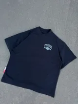 Remera negra de manga corta y corte oversize, con estampa gráfica en blanco en el frente y en la espalda con diseño de tipografía y escudo heráldico.