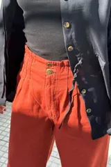 Pantalón jean color ladrillo, de corte ancho, recto y de tiro alto. Tiene elástico y pinzas en la pretina.