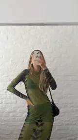 Vestido midi ajustado de microtul verde con estampado abstracto en tonos oscuros. De mangas largas y cuello redondo, es una prenda transparente y elástica.