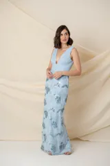 Vestido largo de fiesta color celeste, confeccionado en tul con corsé drapeado de escote profundo y falda bordada con apliques de flores.