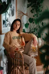 Sweater color crema de algodón con cuello redondo, mangas largas y estampado de Charlie Brown vestido de vaquero con la palabra "Howdy" y cactus.