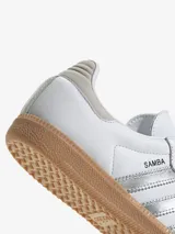 Zapatillas Adidas Samba OG blancas con detalles en plateado y suela de goma color caramelo.