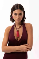 Collar corto con cadena de piedras naturales en tonos tierra y un dije central metálico en forma de herradura del que cuelgan tres borlas de seda en color bordó.