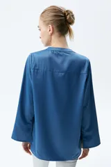 Camisa color crema de satén con botones forrados, cuello en V y manga acampanada tres cuartos.