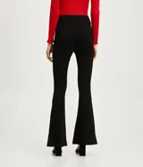 Pantalón flare negro de punto roma, con cintura alta, bolsillos delanteros con botones metálicos estilo escudo y cierre por cremallera y botón.