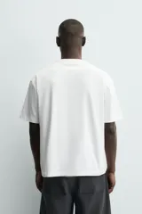 Camiseta de corte relajado confeccionada en algodón con textura irregular, cuello redondo y manga corta.