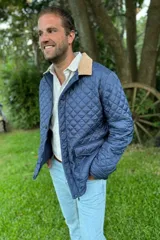 Campera azul marino con diseño capitoneado en forma de rombos y cuello de pana color beige. Tiene cierre frontal con botones a presión, bolsillos laterales y corte clásico.