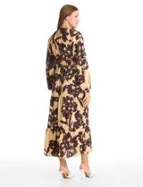 Vestido maxi de crepe con estampado floral en tonos beige y marrón oscuro. Presenta escote en V con botones frontales, mangas largas amplias con puños abotonados y cintura ajustable mediante cordón trenzado. La falda cuenta con un diseño de vuelos escalonados que aporta movimiento.
