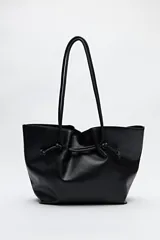 Bolso tipo tote bag negro de cuero sintético, con frunce superior ajustable con cordones y doble asa de hombro.