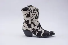 Botas de estilo western (texanas) de caña media, color blanco, confeccionadas en cuero. Presentan bordados decorativos en la caña y puntera cuadrada. Cuentan con cierre lateral y taco de altura media.