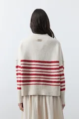 Polera de tejido de punto con diseño a rayas horizontales en color azul marino sobre base beige. Presenta cuello alto, mangas largas con puños acanalados y una silueta relajada.