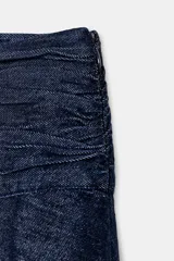 Falda midi de tiro alto con detalle de frunces en la cintura y bajo asimétrico. Presenta cierre lateral con cremallera oculta.