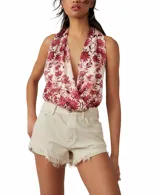 Body sin mangas con estampado floral en tonos rojos y blancos, con escote halter pronunciado y corte alto en las piernas.