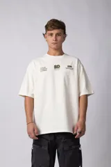Remera de corte oversize color crema, confeccionada en algodón premium. Presenta un diseño minimalista con estampados gráficos en color verde oliva en la parte superior frontal.