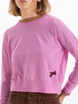 Sweater de tejido de punto en color gris, con cuello redondo, mangas largas y detalle de bordado amarillo en el puño y en el lateral inferior. Presenta un corte recto y estructura ligera.