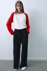 Pantalón de tiro medio color beige, de corte ancho y recto, con pinzas frontales y trabillas en la cintura.