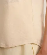 Musculosa deportiva Get Over de microfibra texturizada color marfil, con cuello redondo, tirantes anchos y bajo redondeado.