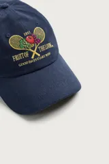 Gorra azul marino con efecto lavado, confeccionada en algodón, con bordado frontal de raquetas de tenis cruzadas con frutas y logo "Fruit of the Loom".