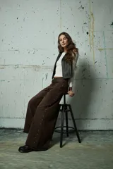 Jean de corte wide leg en color gris lavado, con diseño de aberturas laterales decoradas con tachas metálicas a lo largo de toda la pierna.