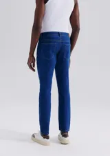 Pantalón de jean de corte slim, color azul, con cierre de botón y cremallera, y bolsillos laterales y traseros.