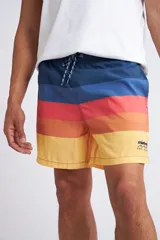 Short de baño con cintura elástica y cordón ajustable, confeccionado en tela ligera de secado rápido. Presenta un estampado botánico integral en tonos amarillos, blancos y azules, con dos bolsillos delanteros y uno posterior.