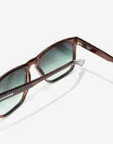 Lentes de sol unisex Hawkers X Pierre Gasly, con montura cuadrada color marrón y lentes degradadas de marrón a verde.