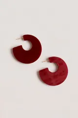 Aros tipo argolla abierta con diseño circular en material de resina color bordó con acabado marmolado.