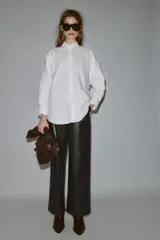 Camisa de corte oversize con cuello solapa, manga larga con puños y bajo asimétrico. Cierre frontal con botones.