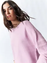 Mochila pequeña color rosa pálido con correas ajustables y asa superior. Tiene un bolsillo frontal con cierre y un parche con el logo de la marca en la parte inferior.