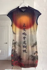Vestido corto de microtúl transparente, con estampado de paisaje asiático al atardecer, tipografía oriental vertical, mangas cortas y cuello redondo.