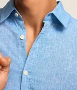 Camisa comfort masculina de lino y algodón color celeste, con cuello inglés, manga larga y abotonado delantero.