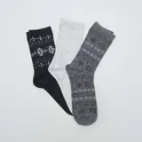 Pack de tres pares de medias de caña media con diseños de jacquard. Un par negro con diseño de copos de nieve blancos, un par gris claro liso y un par gris oscuro con diseño de copos de nieve grises.