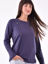 Remera negra de manga larga con cuello redondo y detalle de tachas doradas dispuestas en diagonal sobre el pecho.